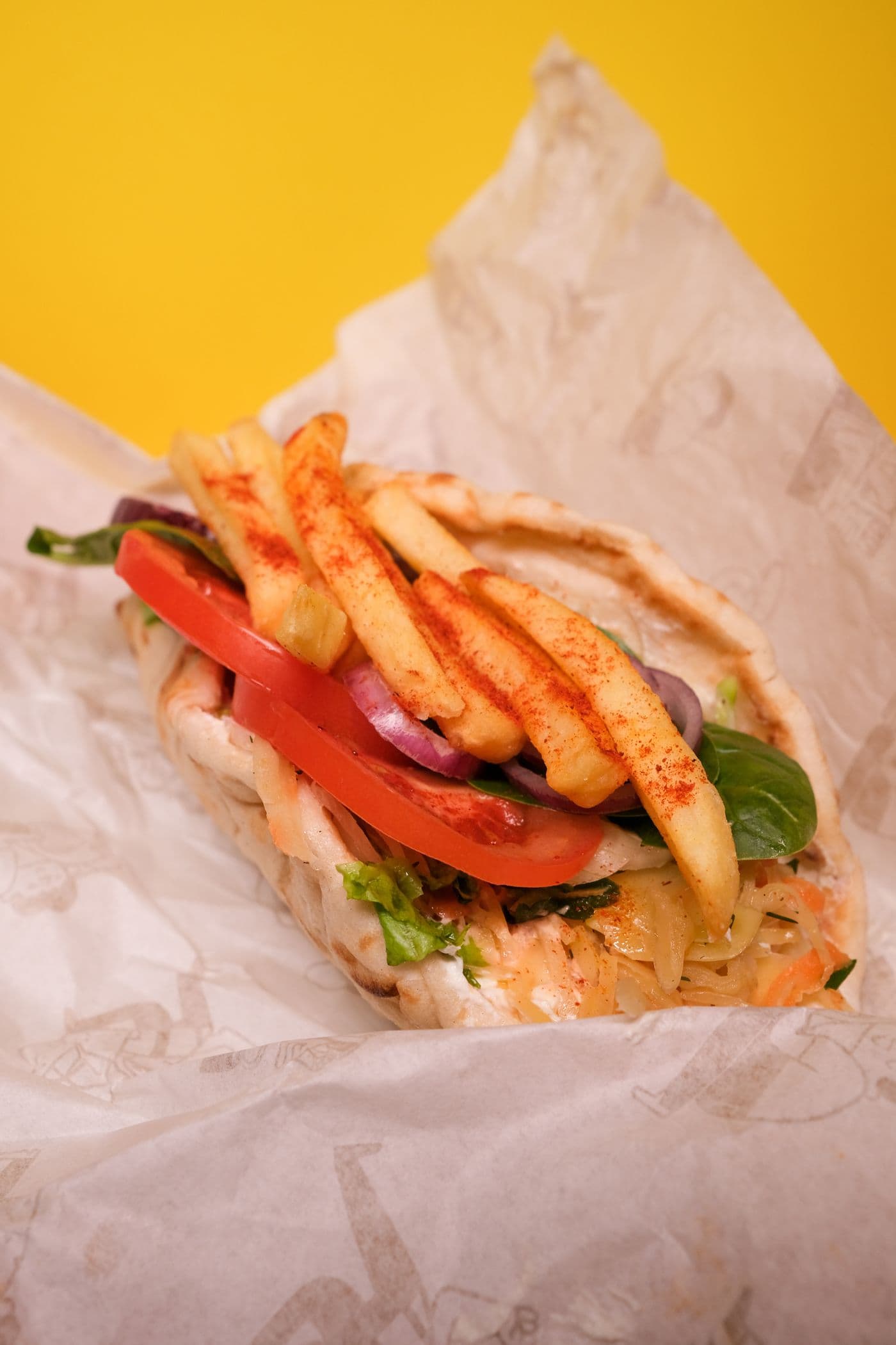 Gyro wrapped in paper against a bright yellow background
